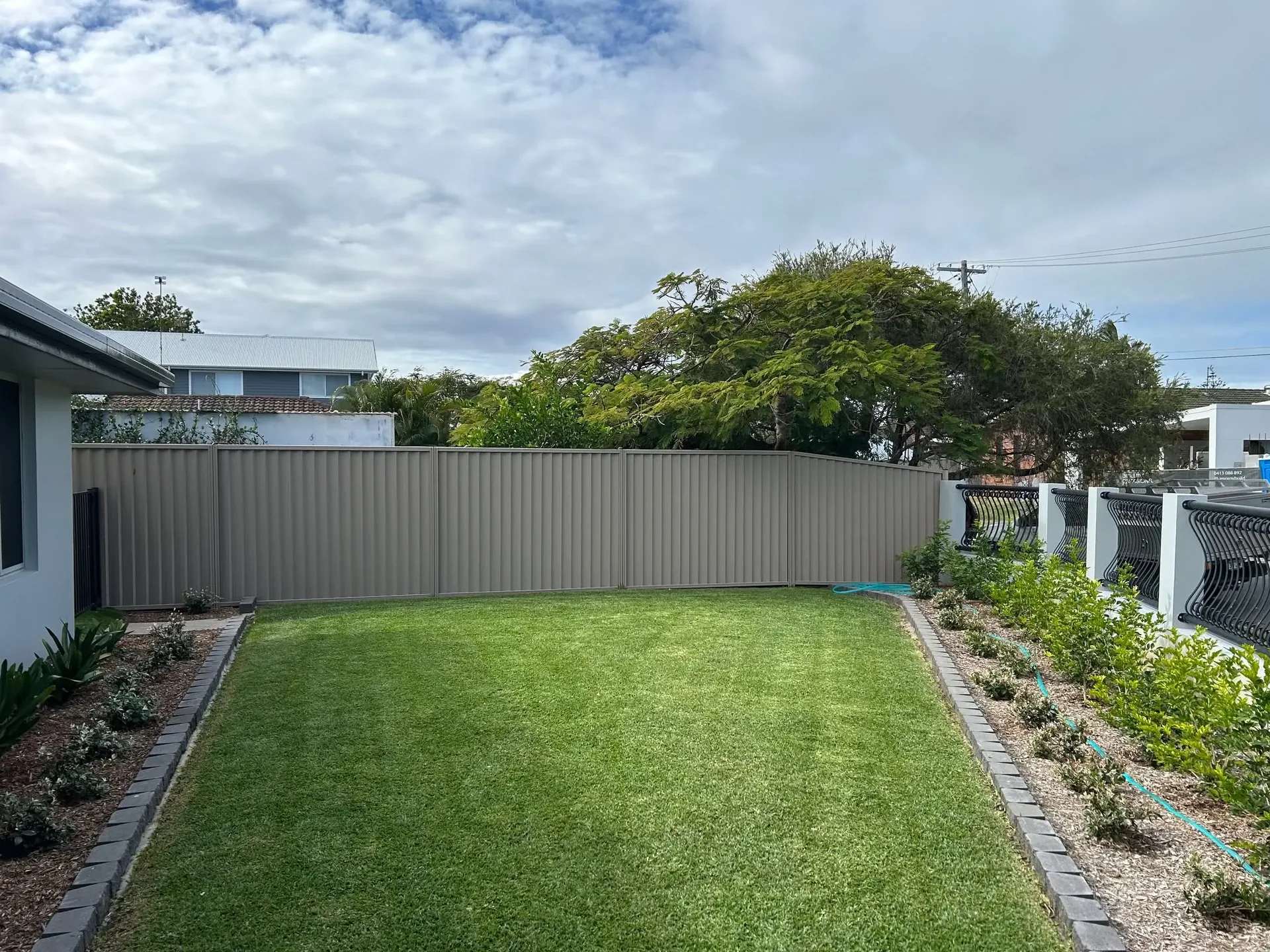 Freshly mown rectangular residential lawn bordered by garden beds